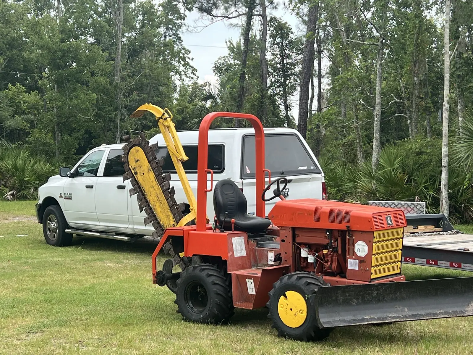 Ride-on chain trencher parked beside the company pickup and trailer before a job in Oviedo, Florida
