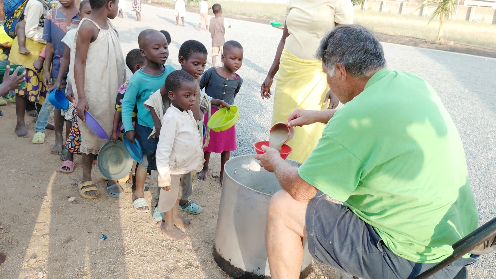Landon Thomas serving hot meals from a large pot to a line of children during an African Missions For Christ Worldwide trip